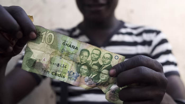 A person holding Ghana cedi notes